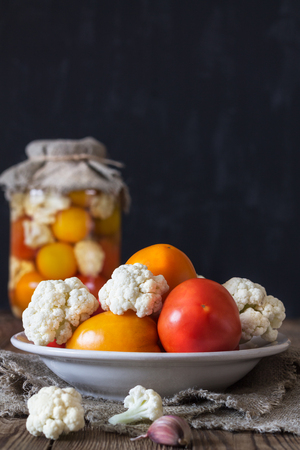 Preparation of fermented vegetables.Fresh tomatoes,cauliflower in a plate in the foreground. Rustic styleの写真素材