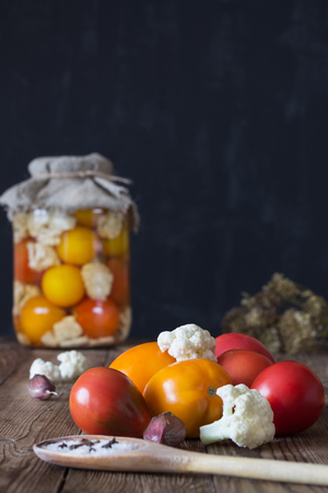 Preparation of fermented vegetables. Fresh tomatoes,cauliflower,spices in the foreground. Dark background. Copy spaceの写真素材