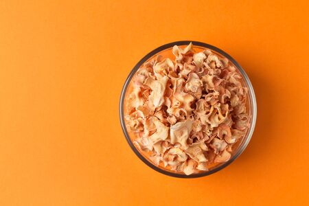 Carrot chips in a glass bowl on a gradient orange background. Minimalistic composition. Healthy...
