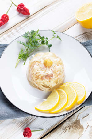 Jelly on a plate with lemon slices, parsley and mustard.