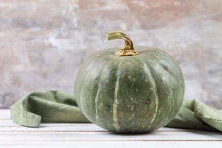 Ripe green pumpkin on a white wooden table.