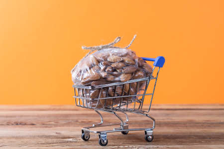 An almond in a plastic bag in a shopping cart on an orange background. Superfoodの写真素材