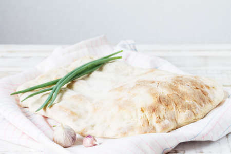 Homemade white tortilla lies on a table towel, with green onions and garlic on a flour sourdough.の写真素材