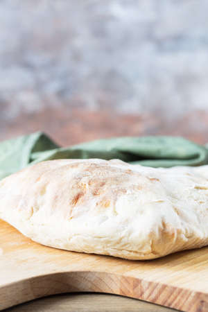 A homemade white puffy tortilla sits on a wooden bread shovel against a blurry background. Bread with flour sourdough.の写真素材