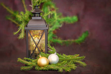 New Year. Ancient lantern, with fir branches, next to two Christmas tree toys in gold and silver colorsの写真素材