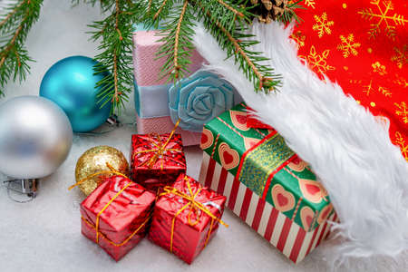 New Year's composition. Gifts in red cap. Christmas tree toys balls and a twig of spruce. Selective...