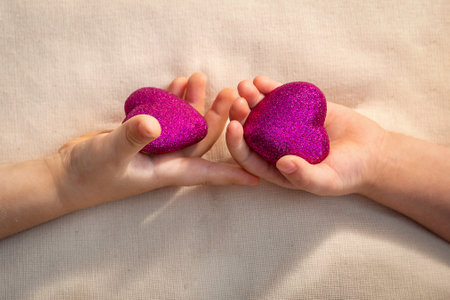 Two children's palms next to each other, in the palms of a scarlet heart. St. Valentine's Day....
