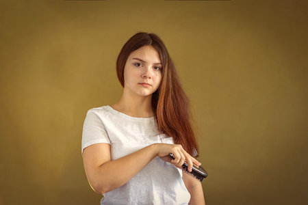 A girl 14-15 years old brushing her long dark hair. Selective Focus