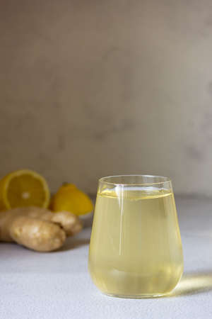 Fermented Kombucha drink in a glass glass. Lemon and ginger in the background. Vertical frame.の写真素材