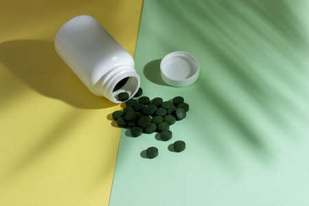Organic spirulina pills flying out of the bottle, place for text, place for text. High quality photo