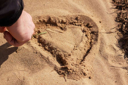 Hand draws a heart in the sand, romanceの写真素材