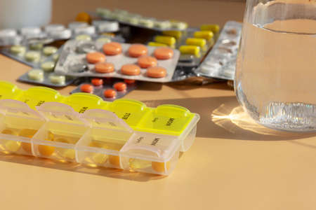 Glass of water and pills on the background of various medicines on the table, space for text