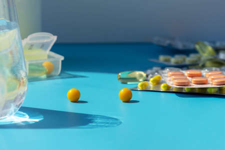 Glass of water and pills on the background of various medicines on the table, space for text
