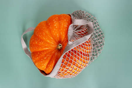 Orange pumpkin in a cotton string bag. Reusable packaging conceptの写真素材