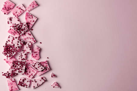 Trendy pink or ruby chocolate with pieces of berries and fruits on a pink background. view from...