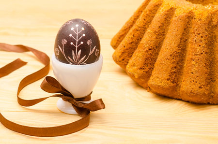 Easter decorative egg and cake on the wooden background