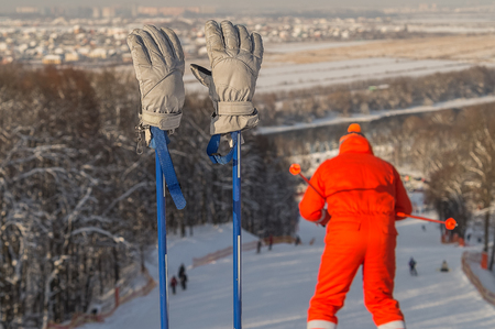 Ski gloves on the ski poles, and a silhouette of skier, skiing down the hill, Moscow region .の写真素材