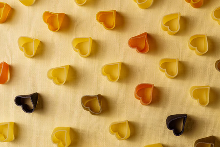 Minimalism style. Repetition concept. View from above on pasta pattern with heart shape, on colored...