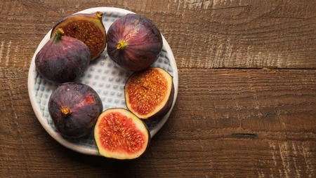 Flat lay view of the plate with ripe fig on old wooden table, copy space.
