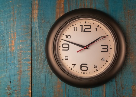 Time concept, Round black wall clock against old wooden blue table.