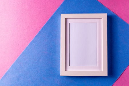 Minimalism style. White empty picture frame against; abstract colored paper background; flat lay.の写真素材