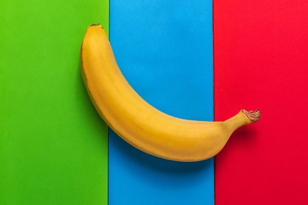 Minimalism style. Food background with ripe yellow banana fruit on colored pastel  paper.の写真素材