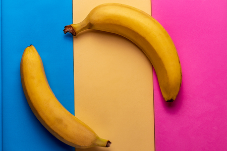 Minimalism style. Food background with ripe yellow banana fruit on colored pastel  paper.の写真素材