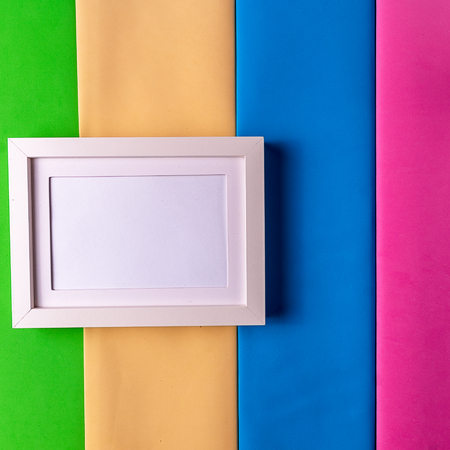 Mockup. Minimalism style. White empty picture frame against; abstract colored paper background; flat lay; copy space.の写真素材
