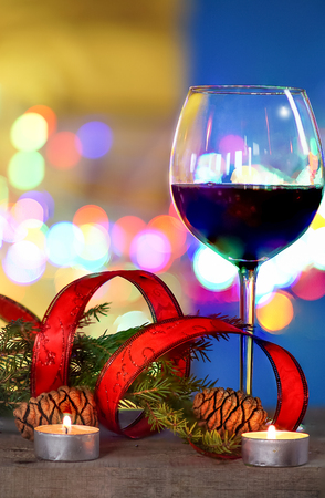 christmas decorations with red wine, candles , red ribbon  and colored blurred background.の写真素材
