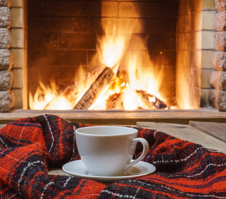 Cup  of  tea, woolen things near cozy fireplace, in country house, winter vacation, horizontal.の写真素材