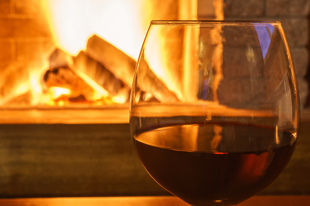 Glass; of red wine , near cozy fireplace in country house, winter vacations, horizontal.の写真素材