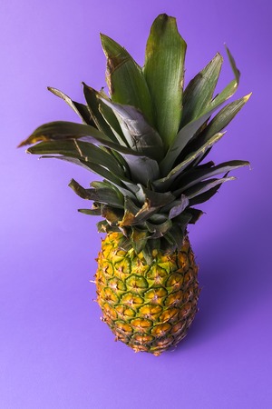 Front view of the ripe pineapple fruit over pastel colored background.