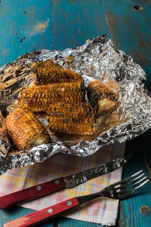 Flat lay view the Grilled corn on a foil over old blue wooden background.の写真素材