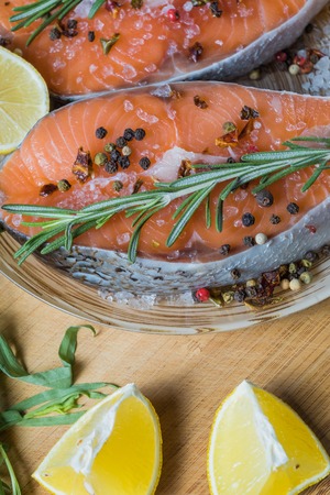 Flat lay view Raw fresh salmon fish before cooking , with lemon and spices, on a plate, over old blue wooden background, close up, vertical.の写真素材