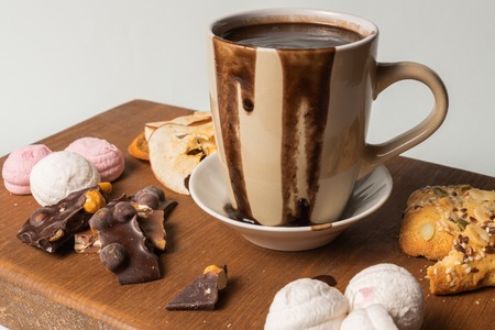 Front view of cup of hot chocolate and marshmallows, and pieces of chocolate and cake.の写真素材