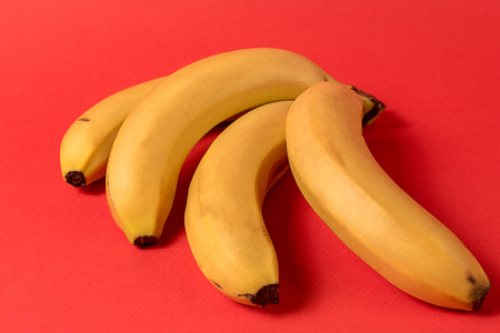 Creative abstract concept. Flat lay view of banana fruit over red background.の写真素材