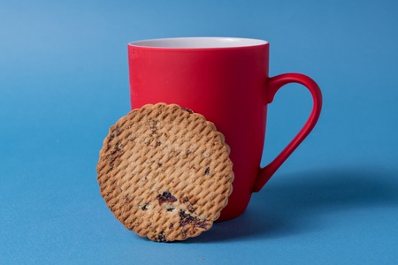 Big red mug and cookie on a blue background.の写真素材