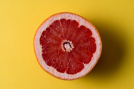 Healthy eating concept. Flat lay view raw fresh red orange fruit over yellow background.の写真素材