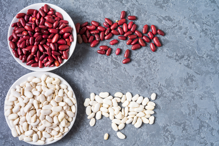 Top view of assortment of white and red beans over gray background, with copy space.