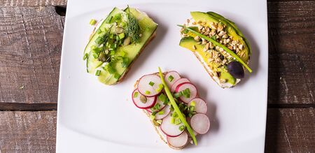 Sandwiches or tapas prepared with cream cheese , vegetables, on a plate, over wooden background....
