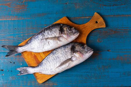 Rustic style. Seabass fish on an old blue wooden background, before cooking, flat lay, copy space.の写真素材