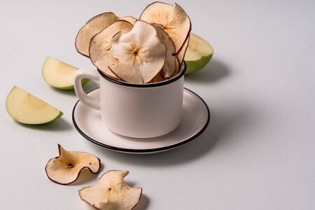 Flat lay Dried apple chips in a cup and fresh apples over light blue background and copy space for text.の写真素材