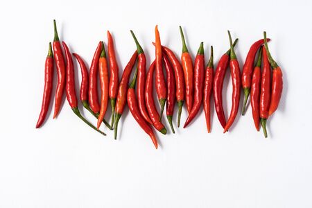 Flat lay Red ripe chili peppers over white background. This condiment could be ingredient of...
