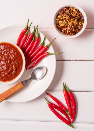 Hot chili pepper sauce paste harissa, traditional Tunisia, Moroccan, Arabic cuisine adjika ,chili pepper spices and fresh red chili peppers, over white background, vertical.の写真素材