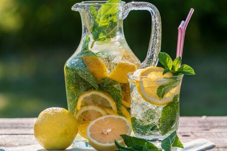Summer concept. Homemade Lemonade with lemon, mint and ice jug and a jar, over old wooden table, outdoor.の写真素材