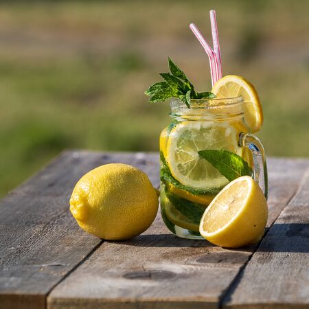 Summer concept. Homemade Lemonade with lemon, mint and ice in a jar, over old wooden table, outdoor.