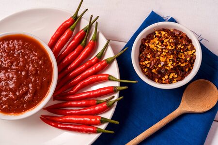 Hot chilli pepper sauce paste harissa, chilli pepper spices and fresh red chilli peppers, over white background.の写真素材