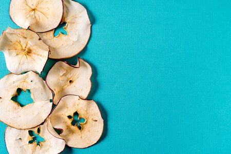 Flat lay Dried apple chips over aqua background with copy space.