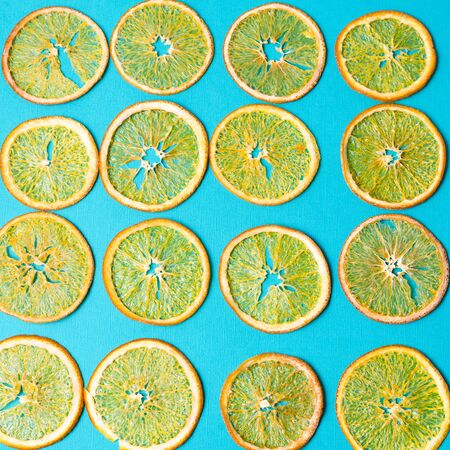 Flat lay a pattern made with Dried orange fruit on blue background.