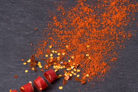 Flat lay red hot Chili peppers, red pepper flakes and chilli powder on black background.の写真素材